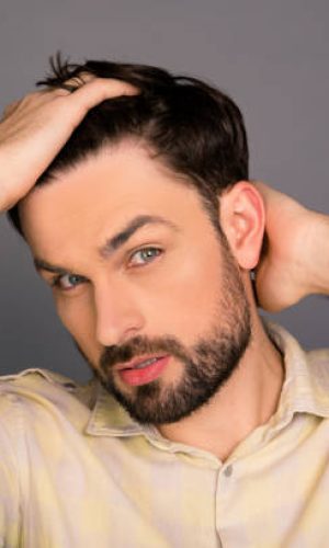 Portrait of handsome bearded man combing hair with fingers